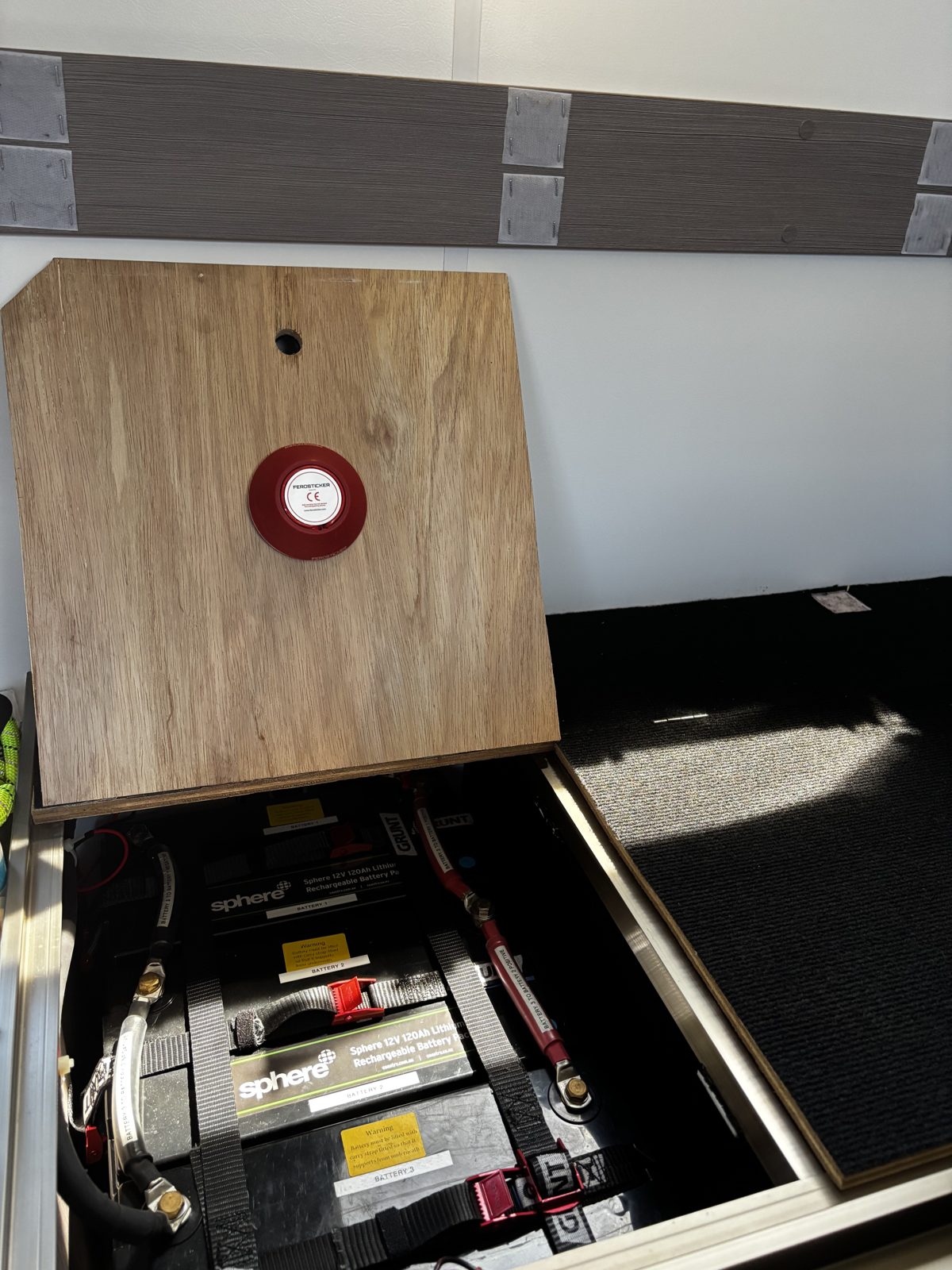 Round Ferosticker device fitted to the underside of the same timber lid above the house battery bay