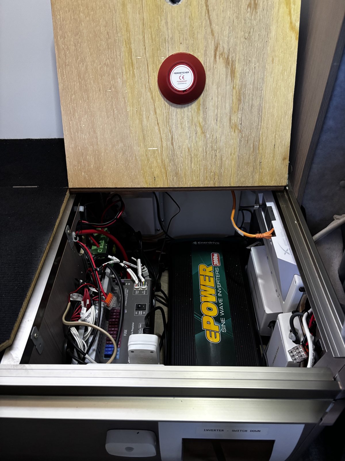 Round Ferosticker device on a timber lid above an inverter and battery bay